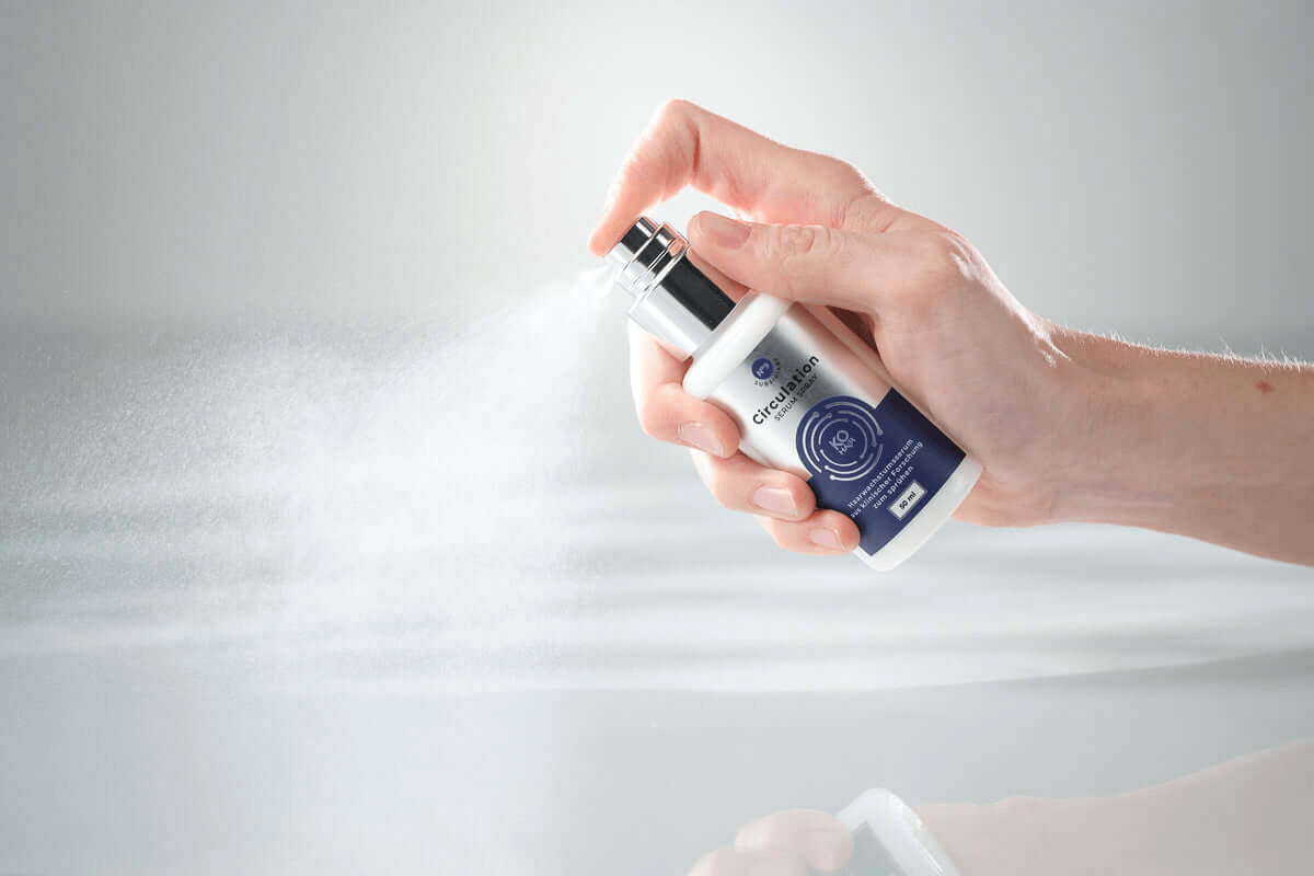 Hand holding KÖ-HAIR Circulation Serum Spray, demonstrating its fine mist application.