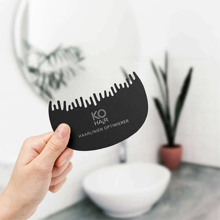 KÖ-HAIR Haarlinien Optimierer in hand, designed for a natural hairline look, set in a modern bathroom.